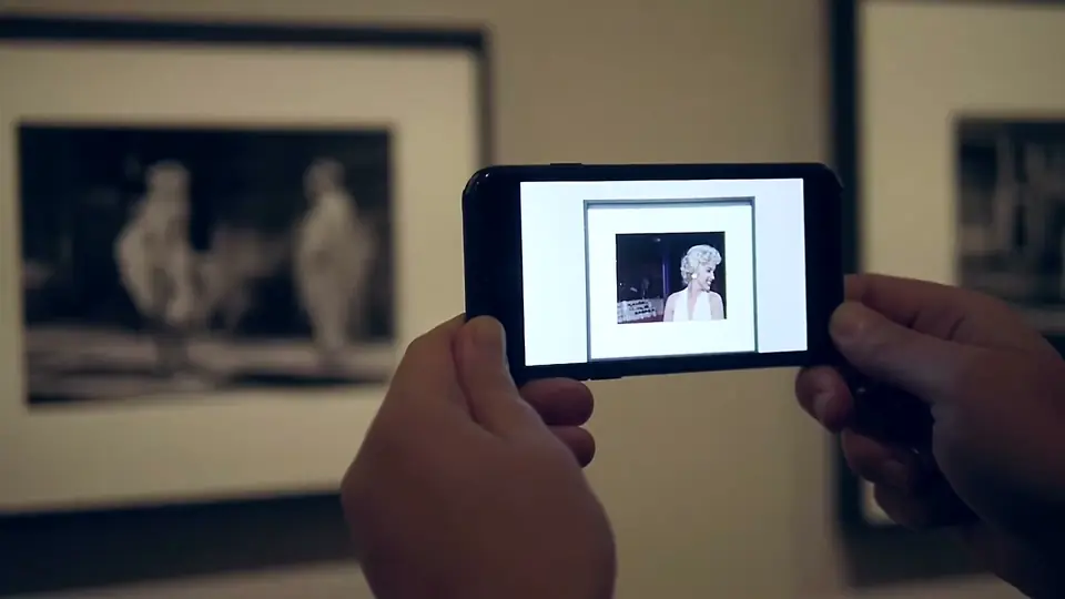 A phone plays the film scene over a film still at the Albertina