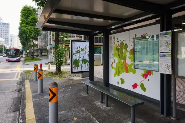 Bus shelter with Andy Yang's artwork of green and red plant shapes on its panels