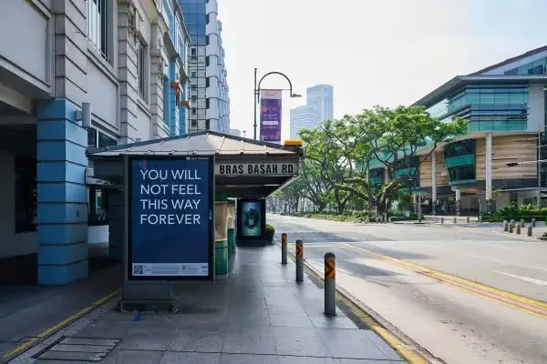Bus stop on Bras Basah Rd with a poster reading YOU WILL NOT FEEL THIS WAY FOREVER, from Andy Yang's AR exhibition