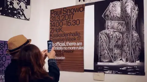 Visitor photographs posters with a phone at the 100 Best Posters exhibition in Vienna, incl. a Paul Snowdon poster