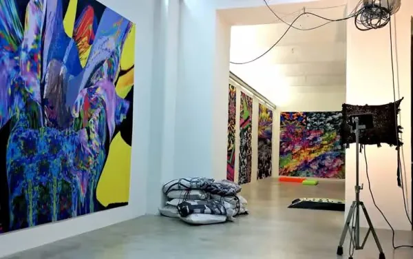 Station Rose gallery space with large vivid digital paintings on the walls and a light on a stand