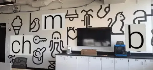 Phone view of the literacy mural with black glyphs and letter tiles like ch, m and b appearing in AR