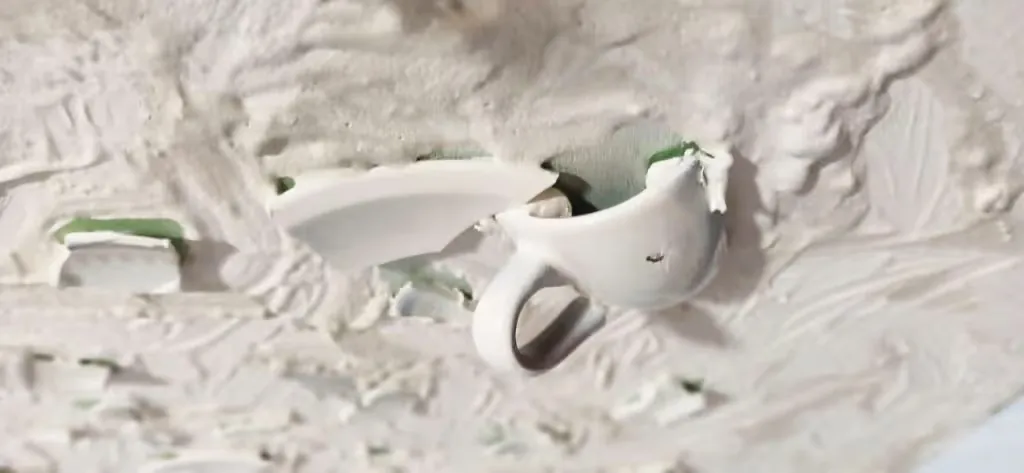 Detail of Pamela Mattana's white ceramic door installation, a broken cup and shards in plaster