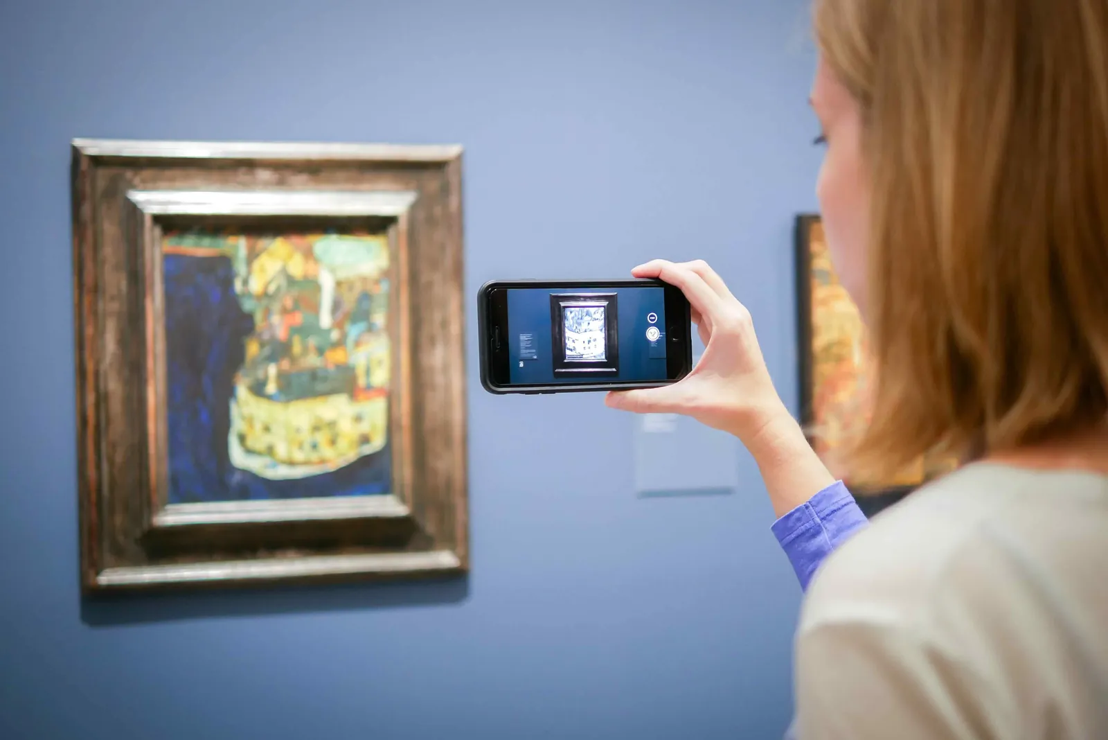 A visitor holds a phone up to a framed Egon Schiele at the Belvedere and sees the painting’s X-ray on screen