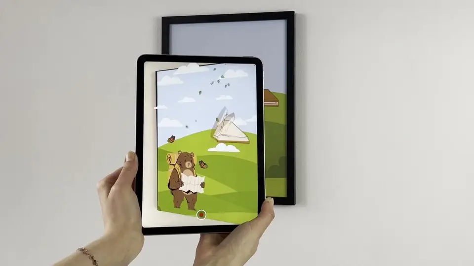 A tablet held in front of a framed print shows the print animated