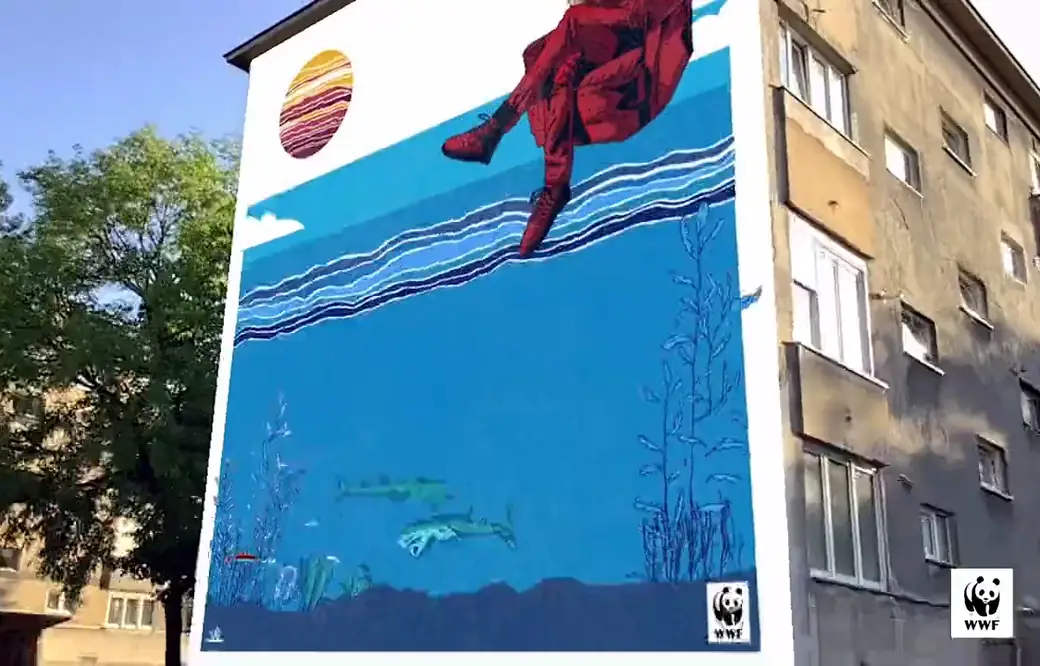 A blue sea mural with a red figure on the side of an apartment block in Zagreb