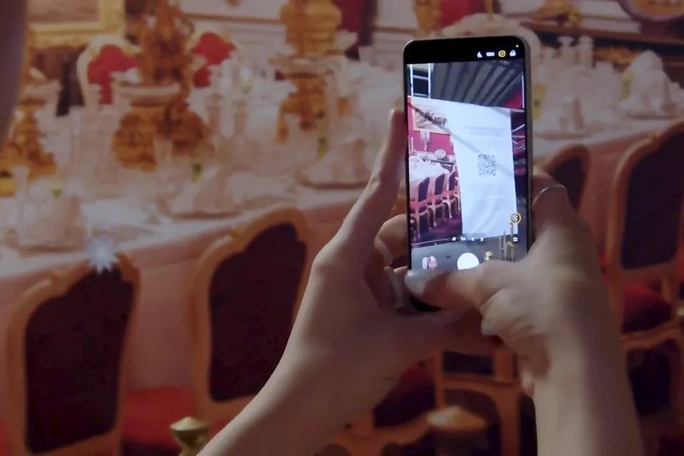 A visitor scans the imperial dining table at the Sisi Museum with a phone