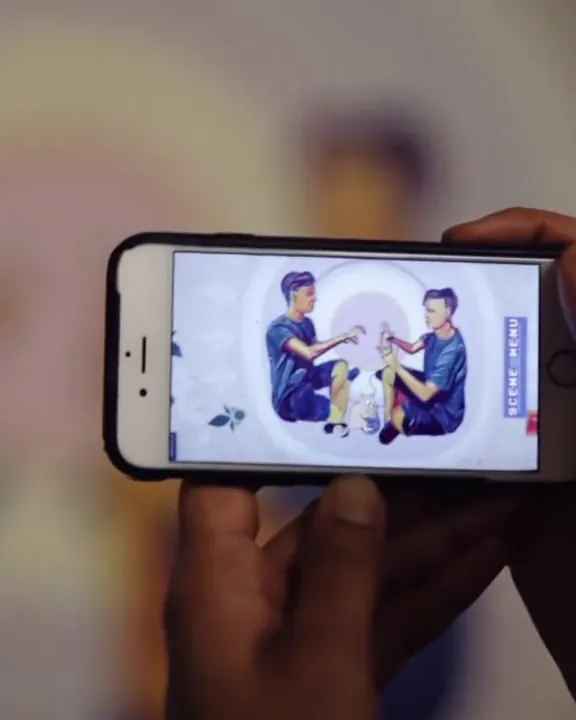 A phone shows the AR animation of a student mural of two people in the MIT tunnels