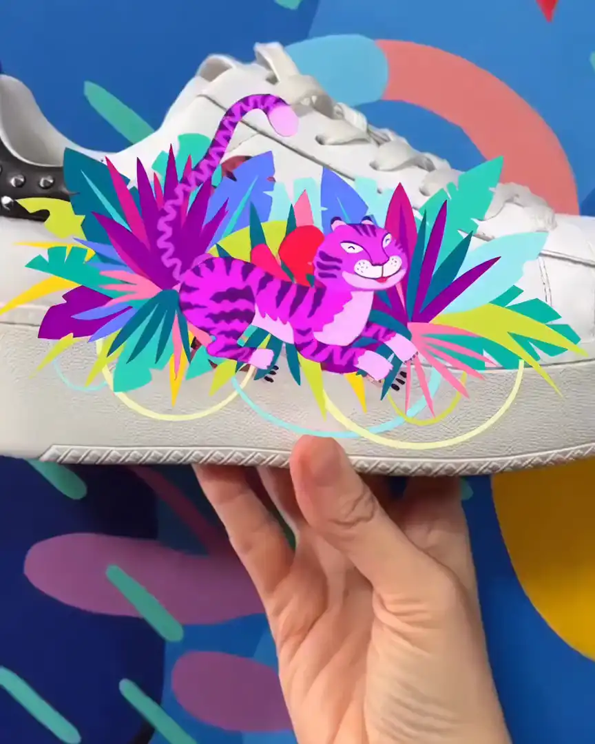 A white sneaker held against a colourful mural; in AR a magenta tiger and tropical leaves burst out of its painted side